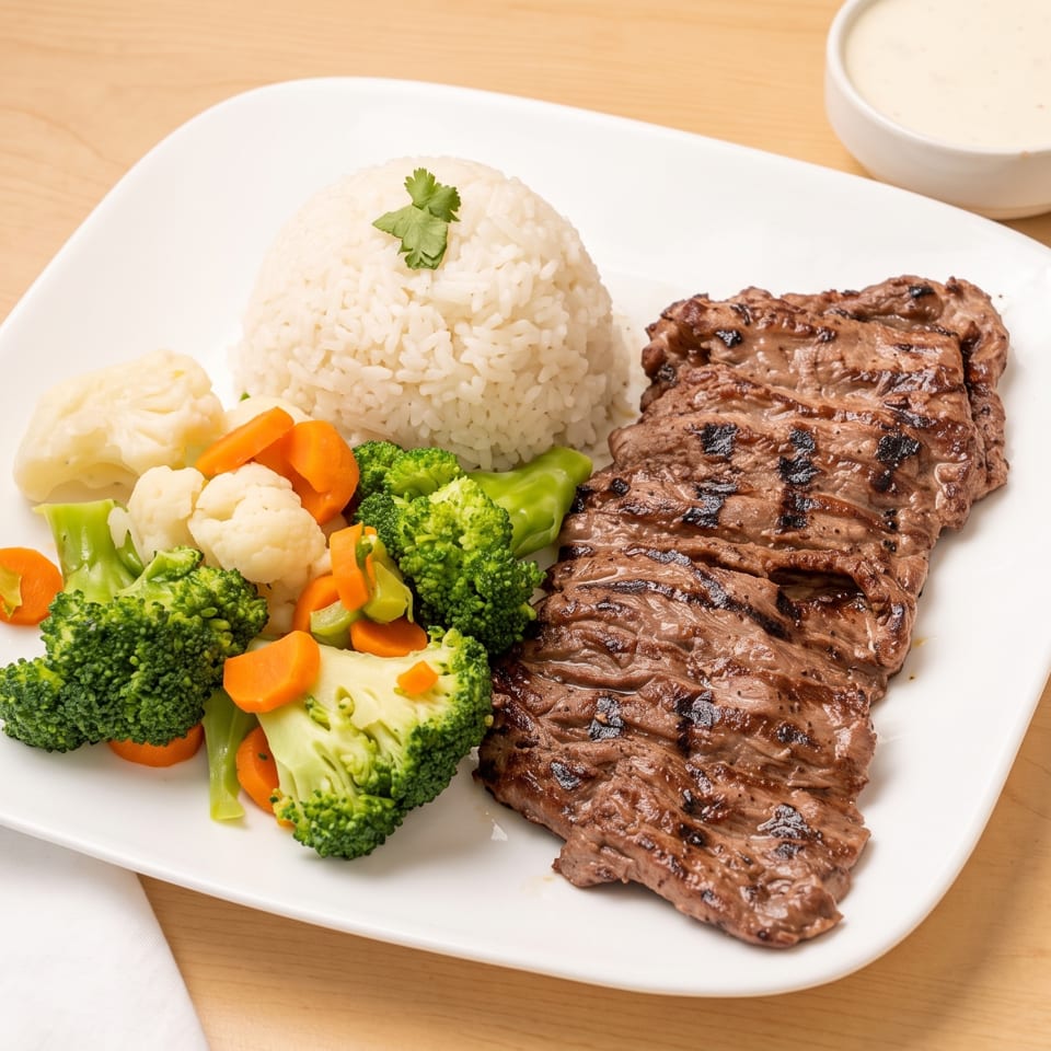 Grilled steak with white rice, steamed broccoli, cauliflower, and carrots, served with three dipping sauces.